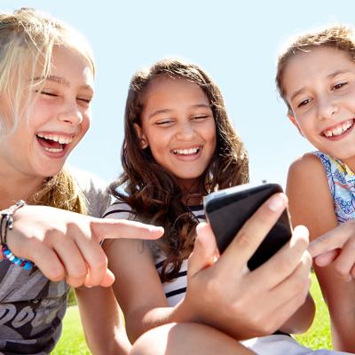 A group of three young girls laughing at content on social media.