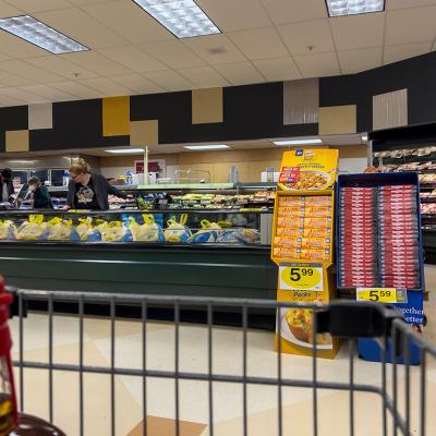 Wide view of people shopping for Butterball Thanksgiving turkeys inside a grocery store.