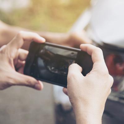 An insurance agent taking a photo of a car's damage.