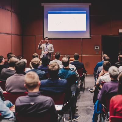 An audience in a conference room listening to a speaker.