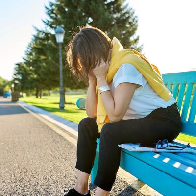 A tired woman sitting on a bench in the park, taking a break from fitness run.