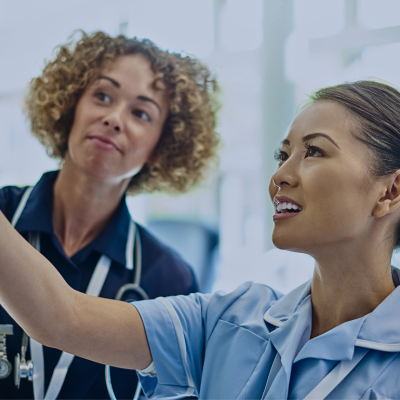 Two women nurses are looking at the ivy in front of them.