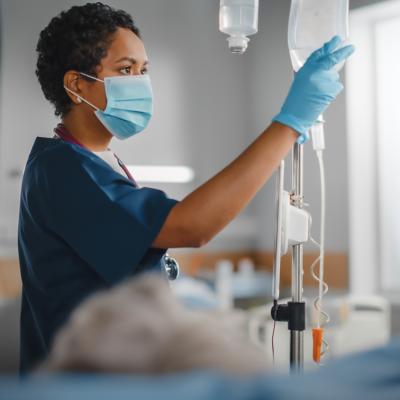 A nurse wearing a face mask checking a patient's vitals