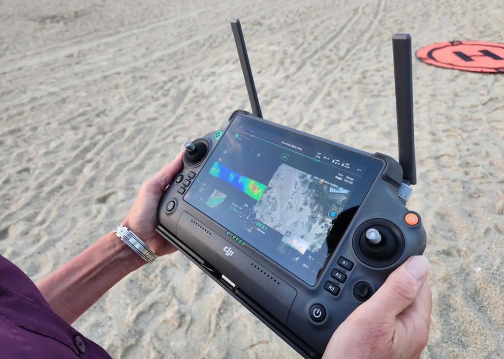 Close up of the drone console in Claudia Venherm's hands as she pilots a drone over the south end of Tybee Island, photographing and measuring the dunes and beach. 