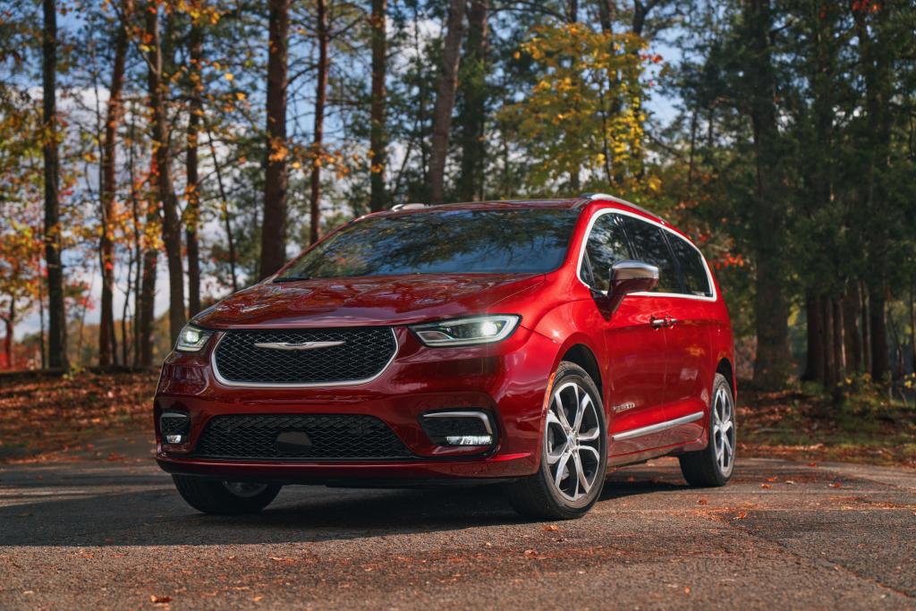 A red 2024 Chrysler Pacifica minivan parked outside in nature.