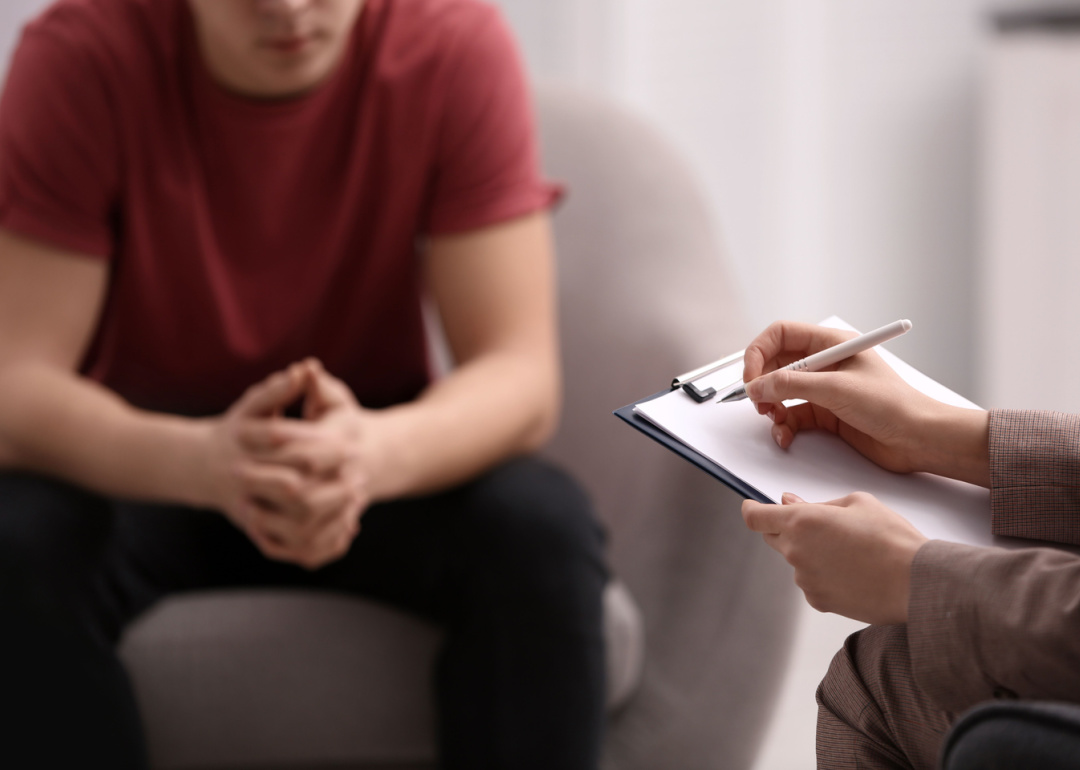 Therapist writing on a clipboard in a session with a patient.