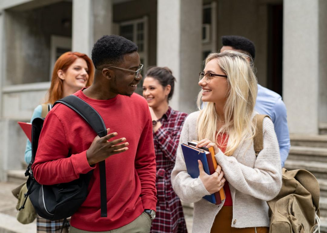 Group of international students walking outside college building.