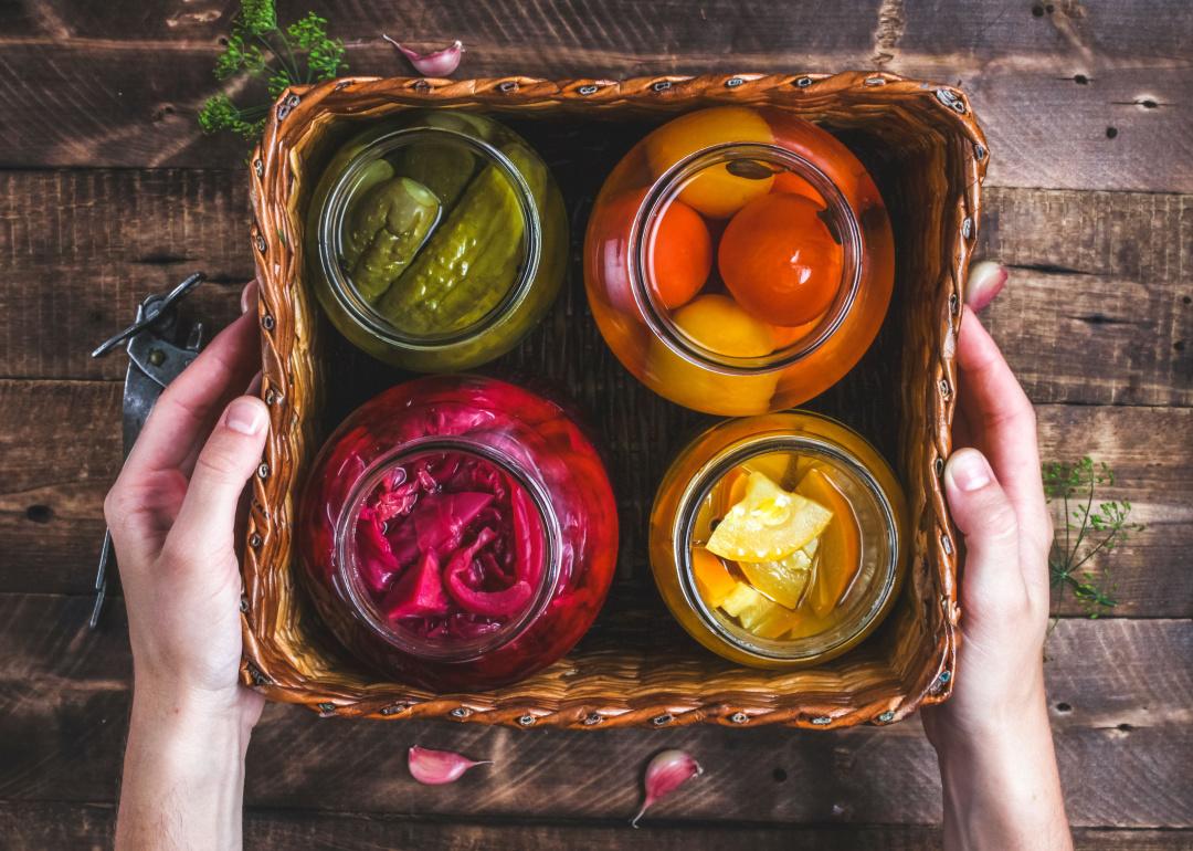 Glass jars of homemade pickled vegetables in box.