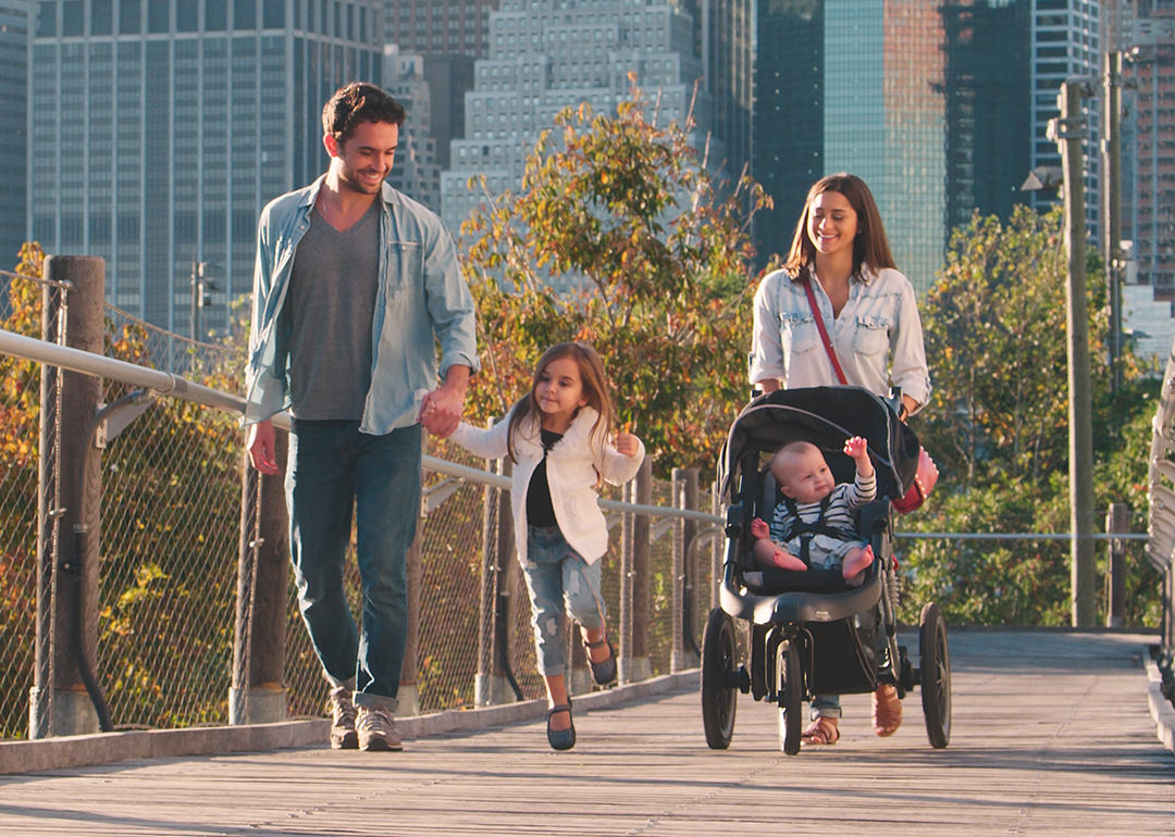Family with stroller and city skyline in the background.