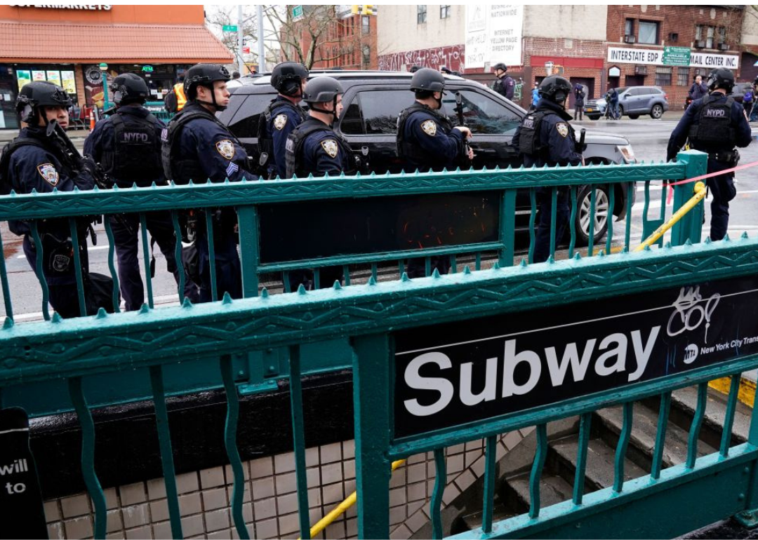 Photo of a subway sign with police officers behind it