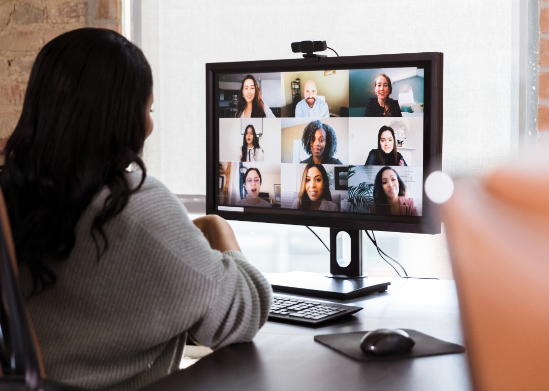 Businesswoman talks with colleagues during virtual meeting.
