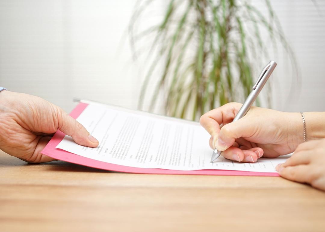 Boss gives employee layoff contract to sign.