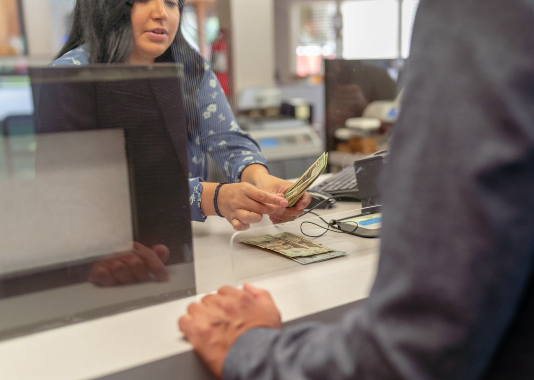 Bank teller counting money for customer.