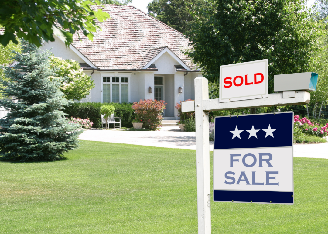 A photo of a home with a for sale sign in the front yard.