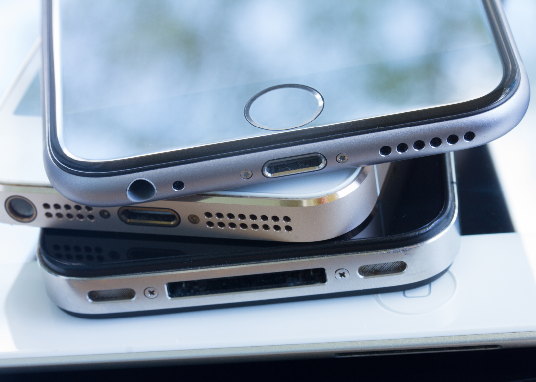 A close-up of a stack of smartphones on a desk.