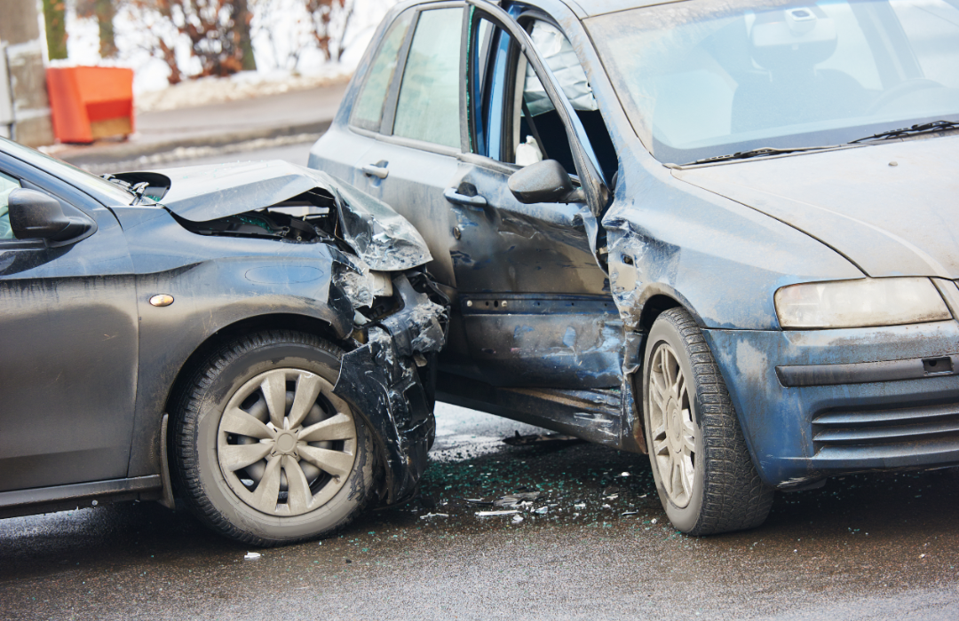 Aftermath of one car crashing into the front-seat passenger side of another car on the street.