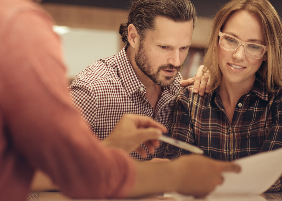 A couple reviews financial documents with a loan officer.