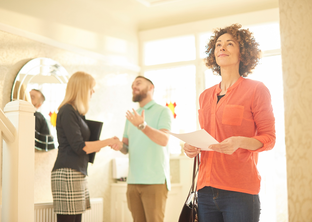 A couple standing in their new home; the man is shaking hands with a female realtor
