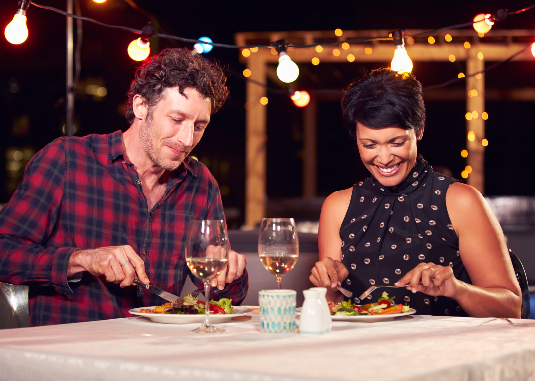 A couple enjoying a rooftop meal at night.