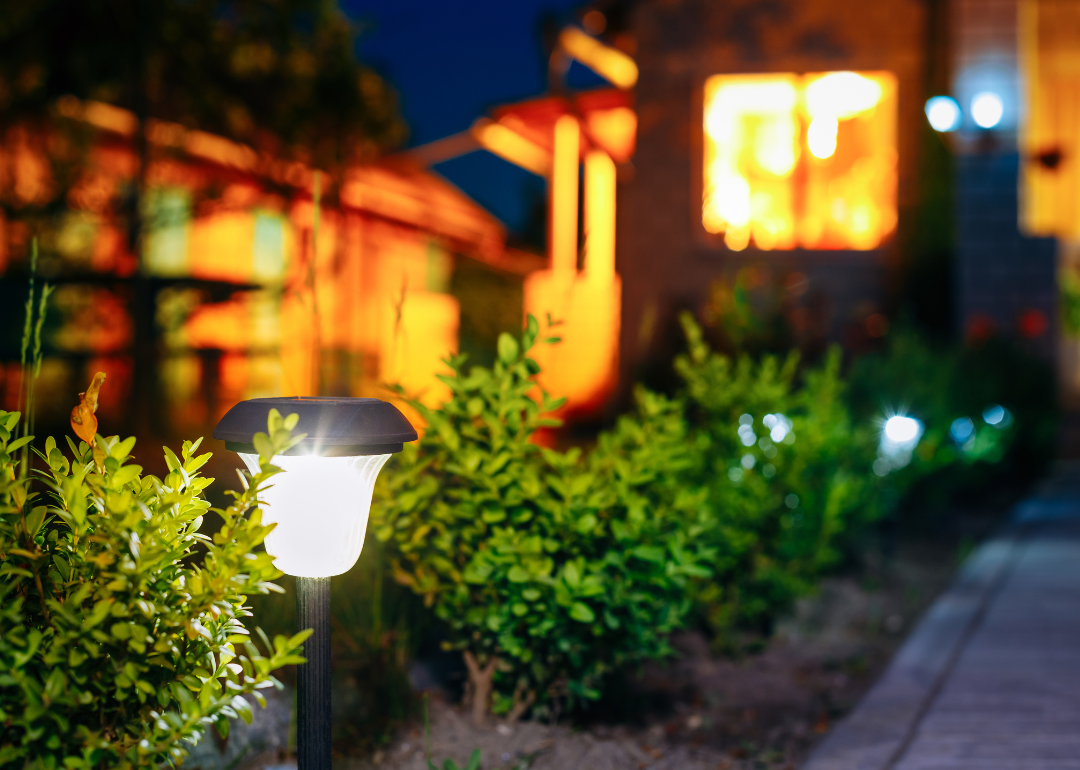 A solar powered light in a landscaped backyard at night.