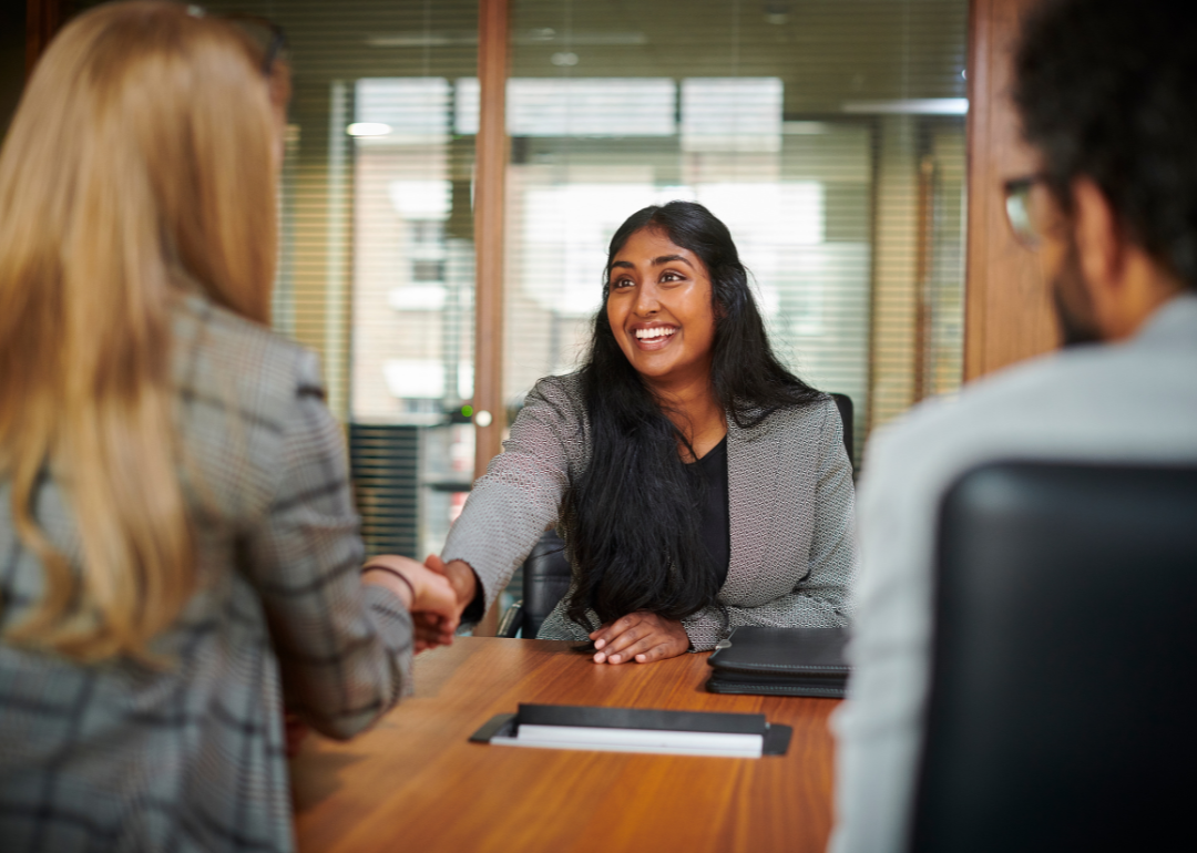 A woman smiling and shaking hands at a job interview