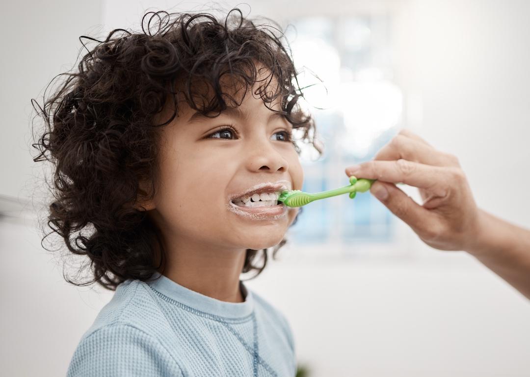 A parent brushing their child's teeth in the bathroom at home.