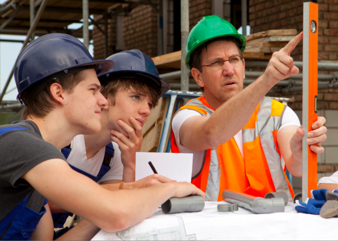 Two adolescent boys are fully focused on the level being held by their instructor.
