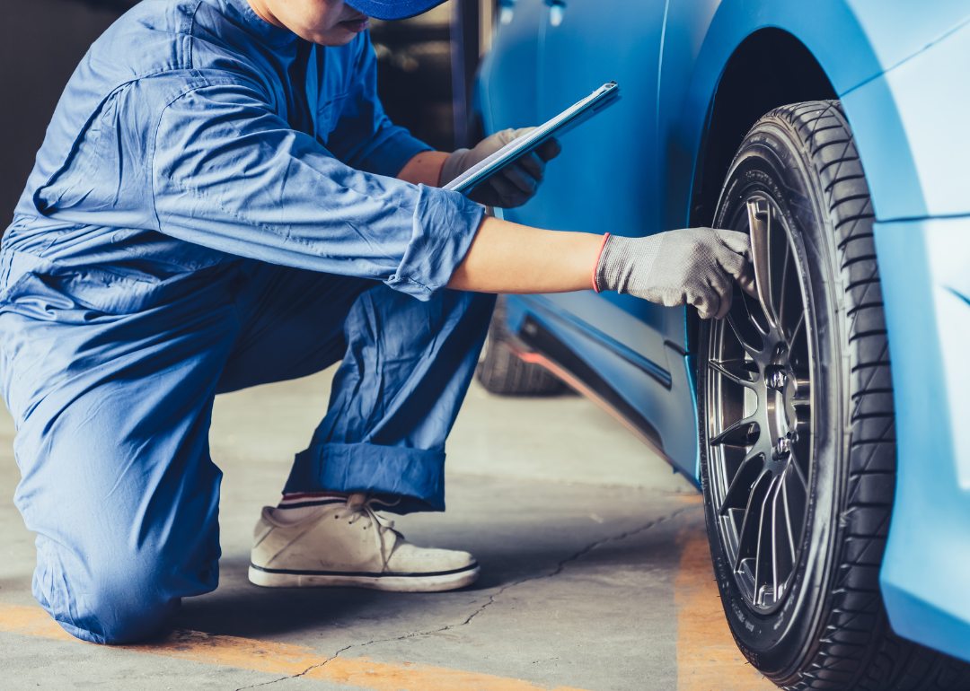 An automotive technician inspecting a vehicle's tires