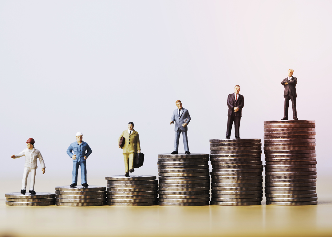 An image showing steadily growing piles of coins topped with small figures of workers dressed to 'match' a perceived income level