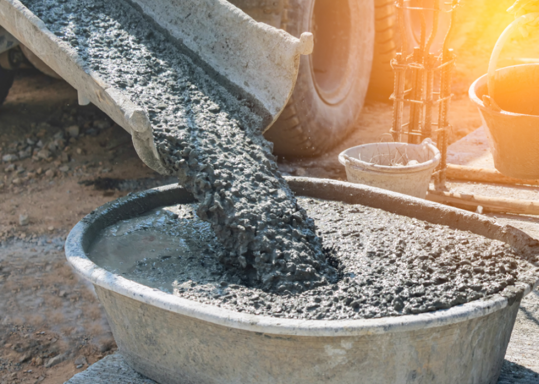 Close-up of concrete mixer truck pouring concrete into large basin.