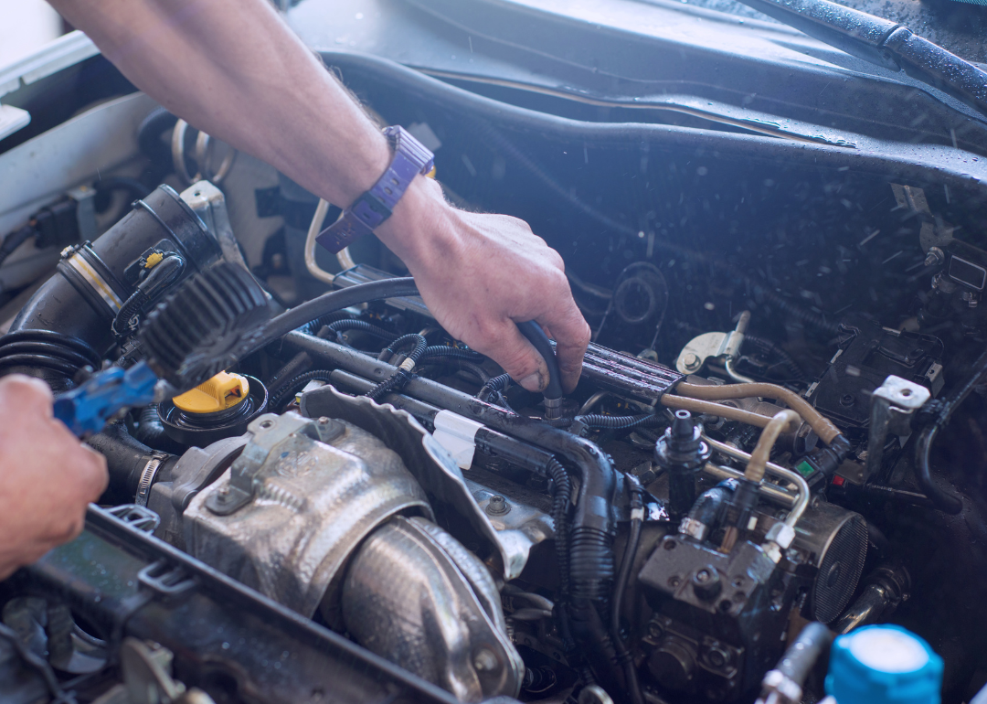 An auto mechanic works on a car engine
