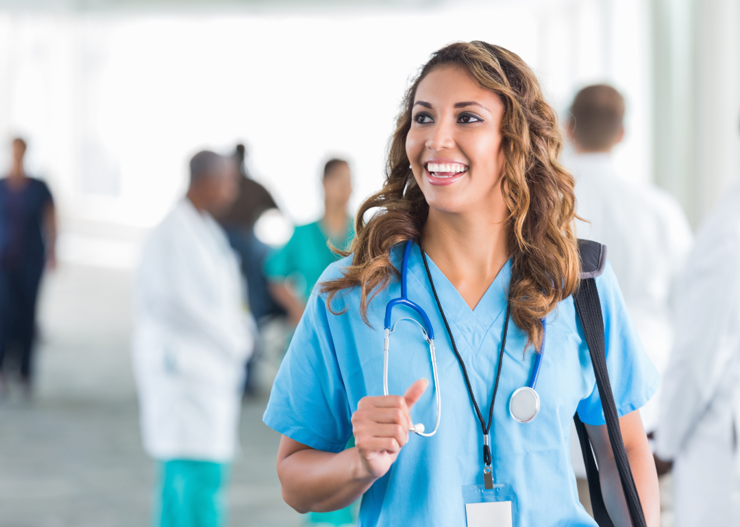 A female nurse with brown hair looking off-camera and smiling