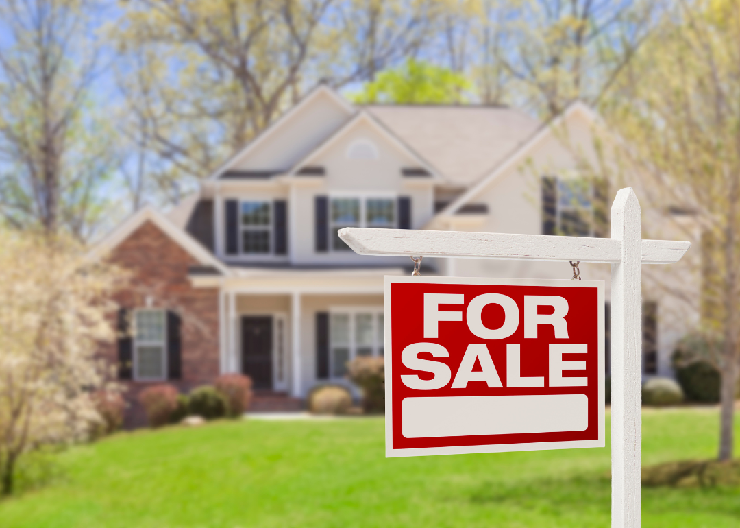 A For Sale sign in front of a single-family home