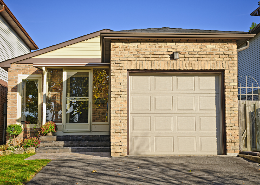 A brown brick starter home with one-car garage