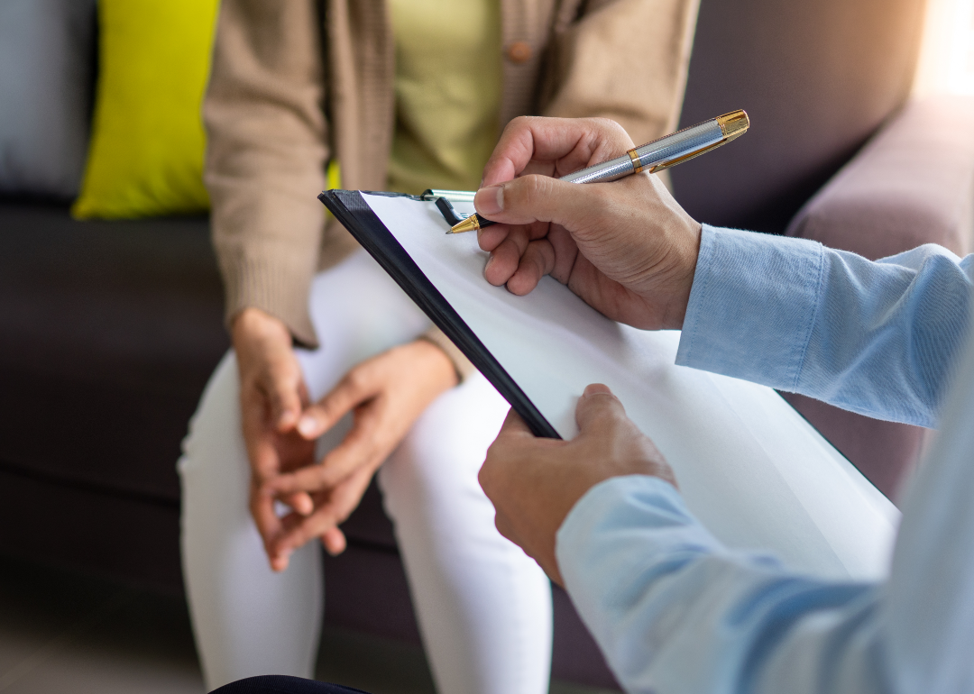 Closeup of therapist writing down notes during a mental health care appointment with a patient.