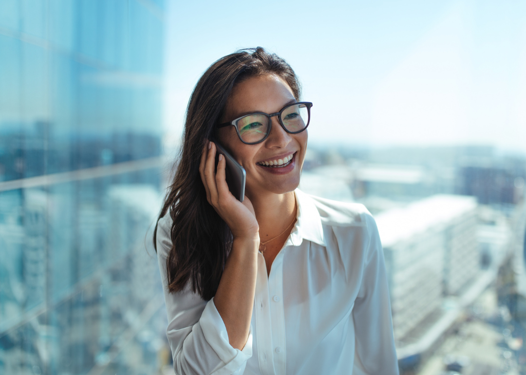 A smiling young woman in glasses talks on a smartphone