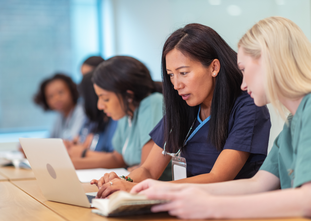 Group of nursing students sit at desk in front of a computer.