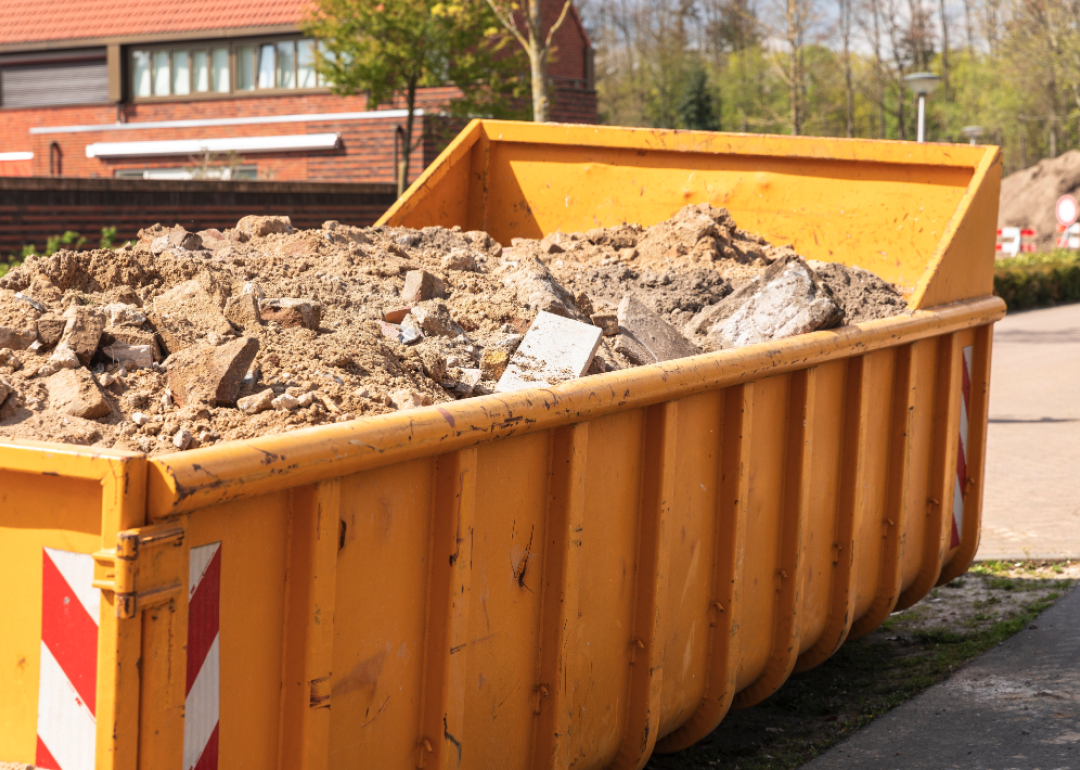 Debris from destruction of a building in a yellow container on a work site.