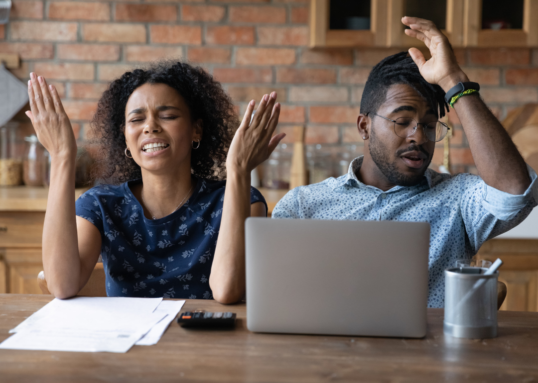 A young Black couple is expressing frustration over financial documents