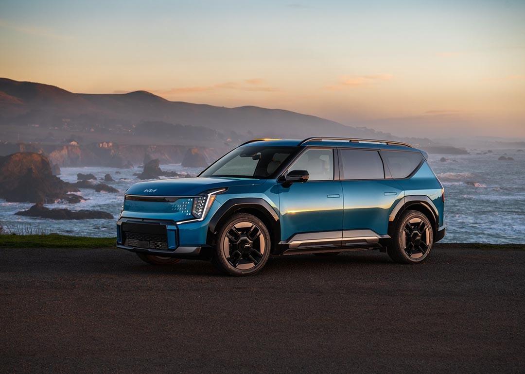 blue kia ev9 parked by ocean