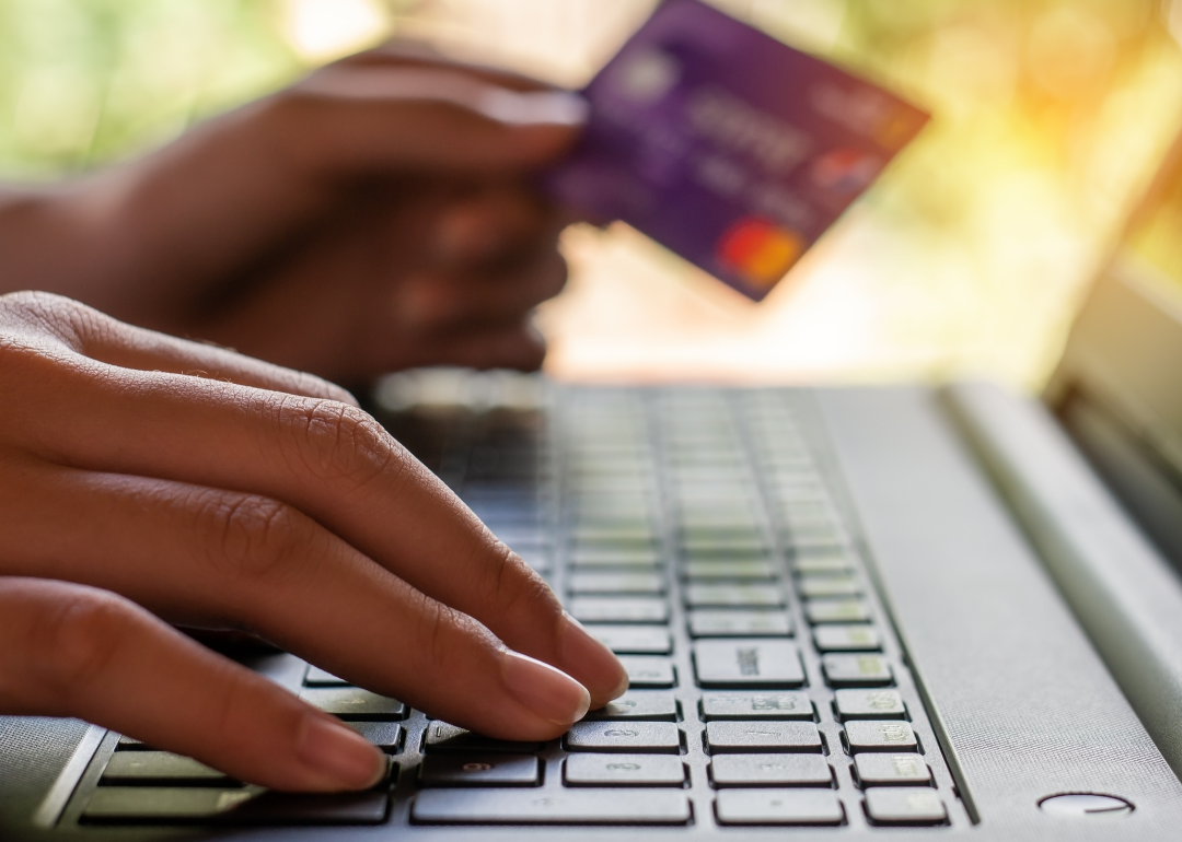 closeup of person using computer keyboard with bank card in hand
