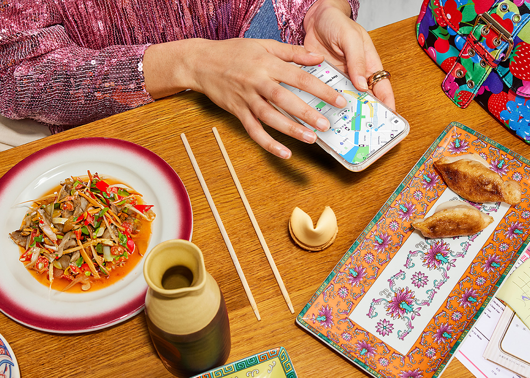 overhead photo of diner in front of chinese food meal while using lyft app on phone