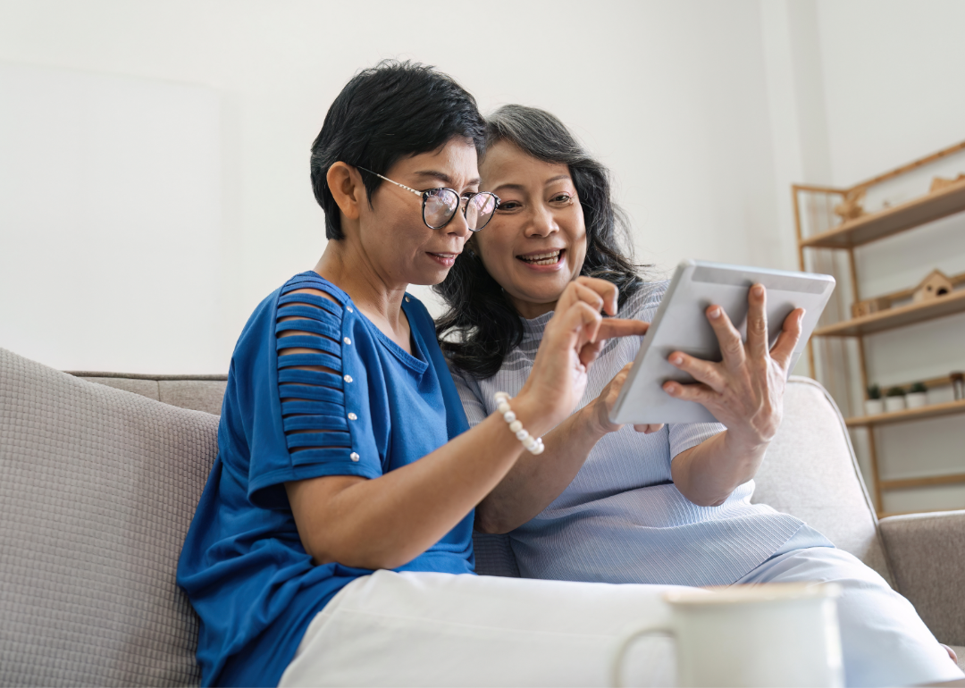 two senior friends use a tablet together