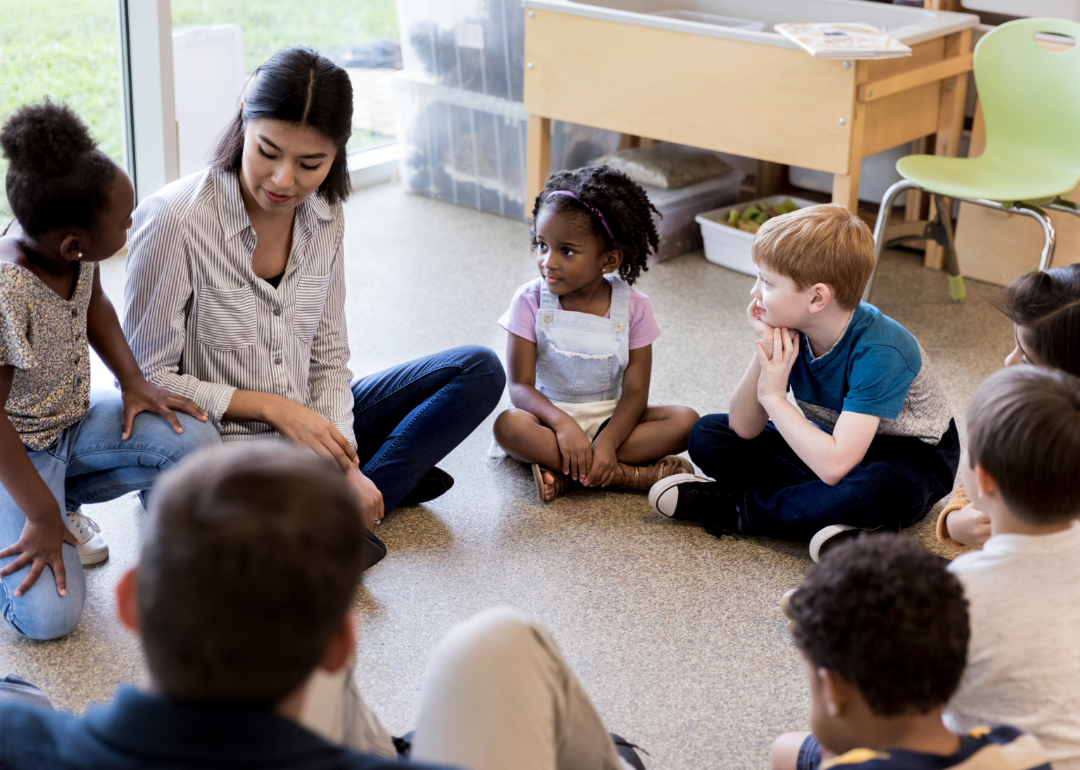 elementary school students sitting in a circle talking to teacher