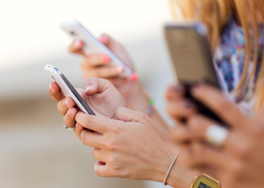 Close-up of several hands holding smartphones.