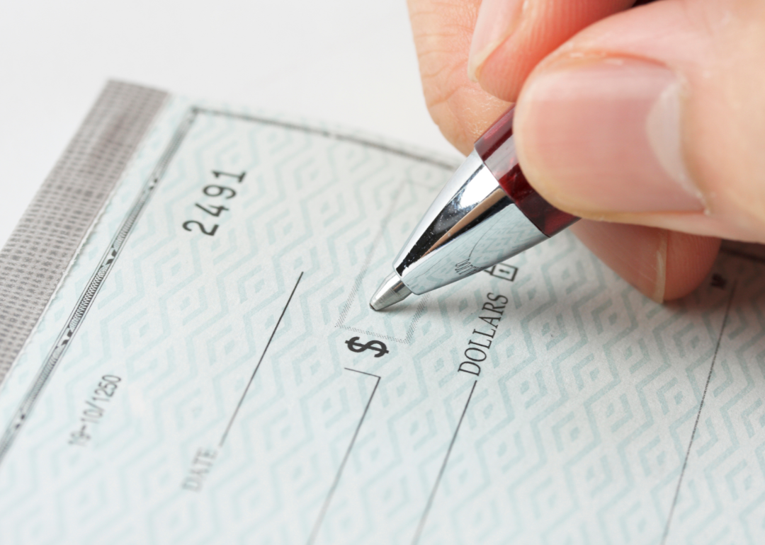 close up of hand and pen writing a check