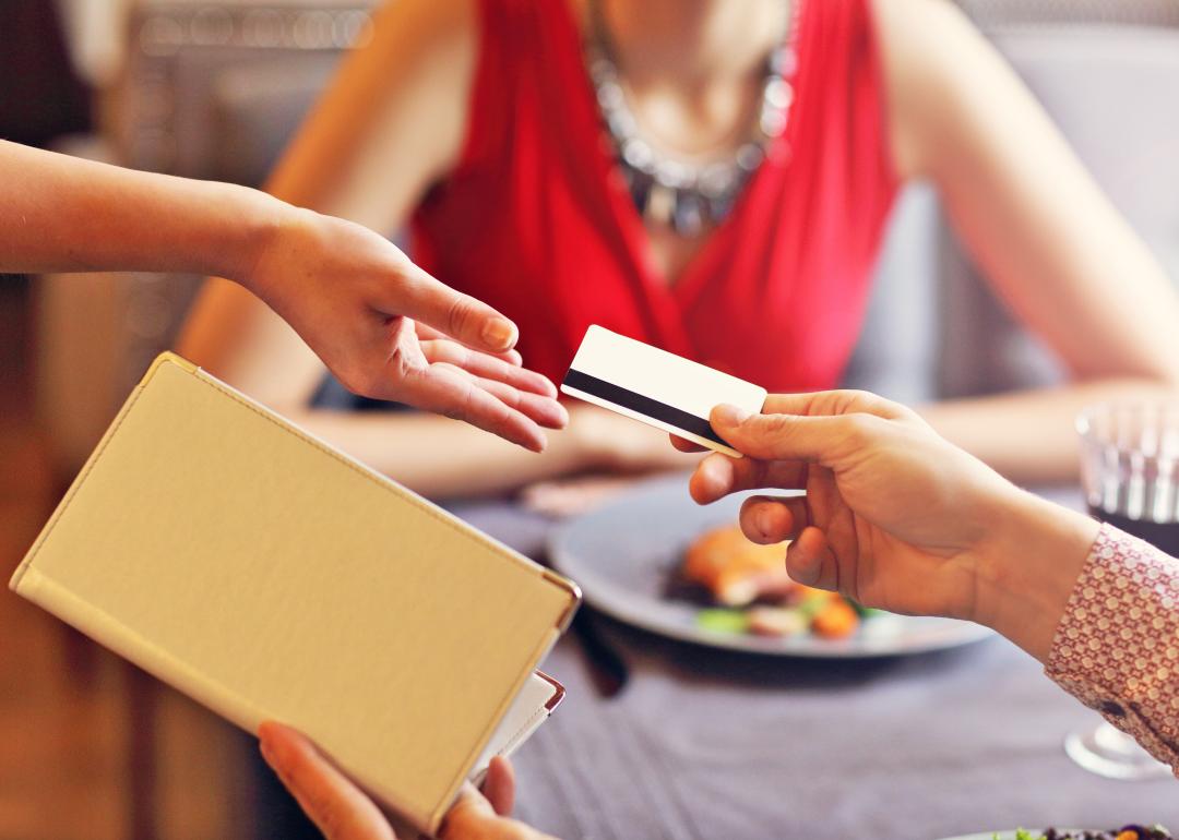 person paying for dinner with credit card with blurred image of date in the background