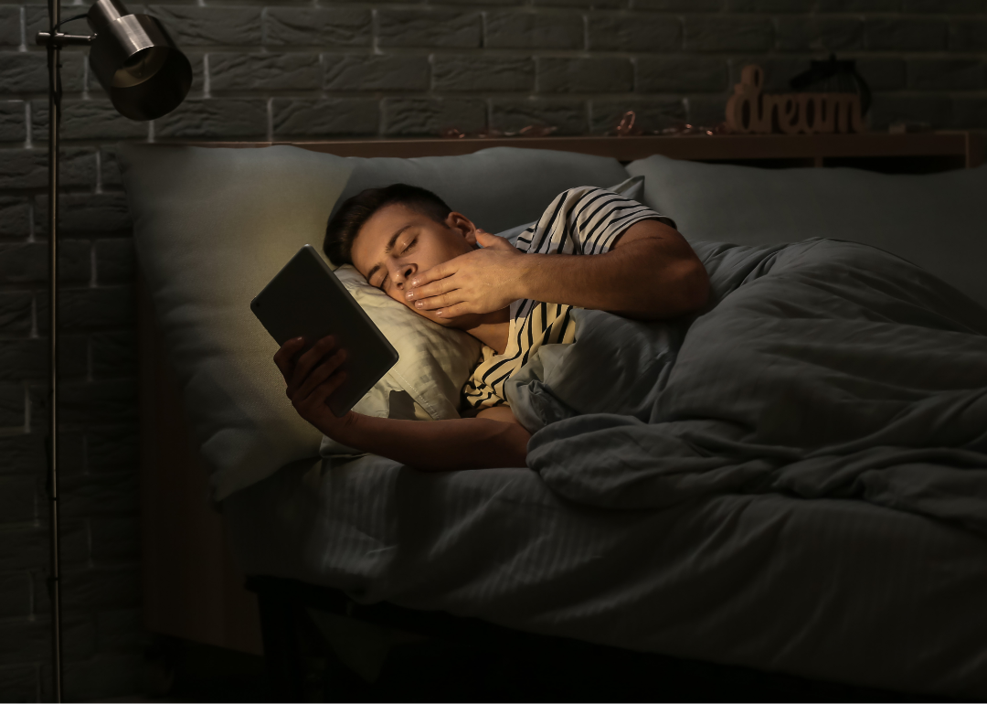 man using ipad in bed with the lights off