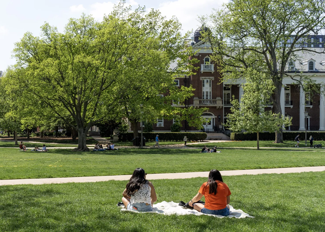 students sitting on the lawn at a college campus