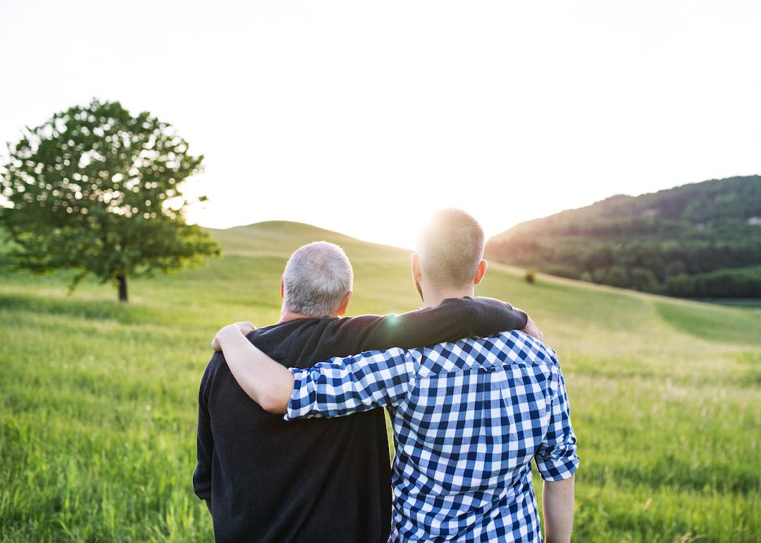 Two people stand with their arms around each other watching the sunset in rural America.